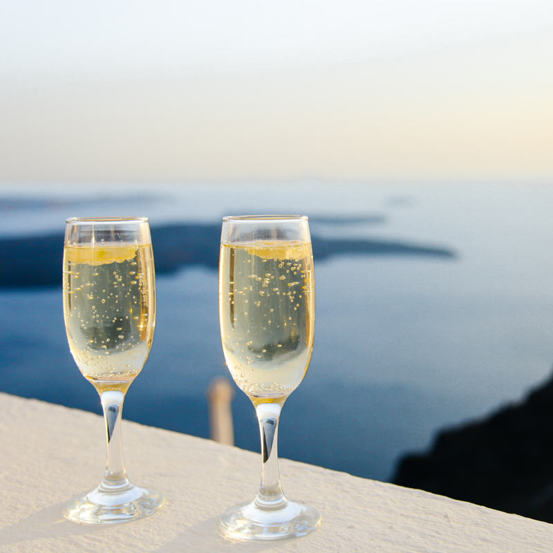 two glasses of sparkling wine on a ledge overlooking a body of water
